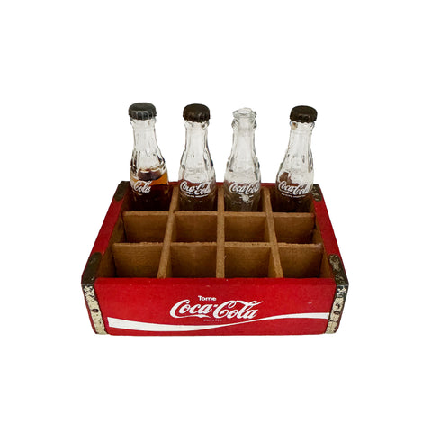 A vintage crate of 4 Coca Cola bottles in miniature one has contents 