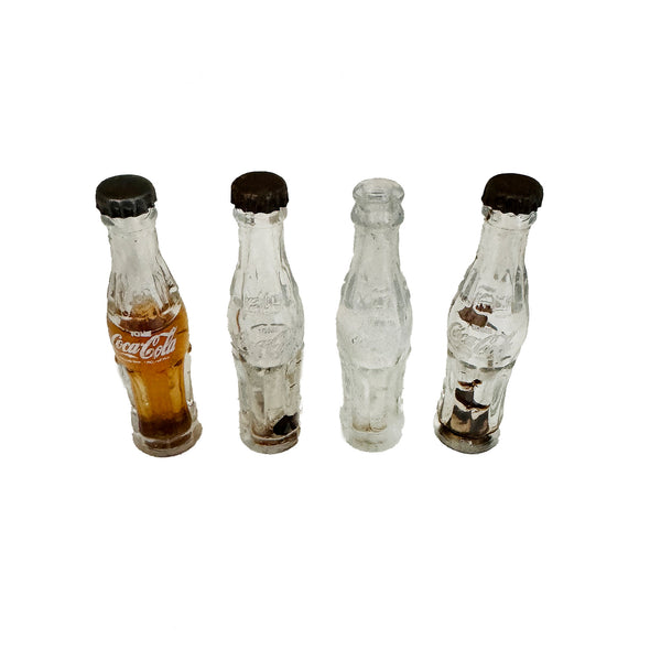 4 miniature bottles of Coca Cola missing top and 1 half full