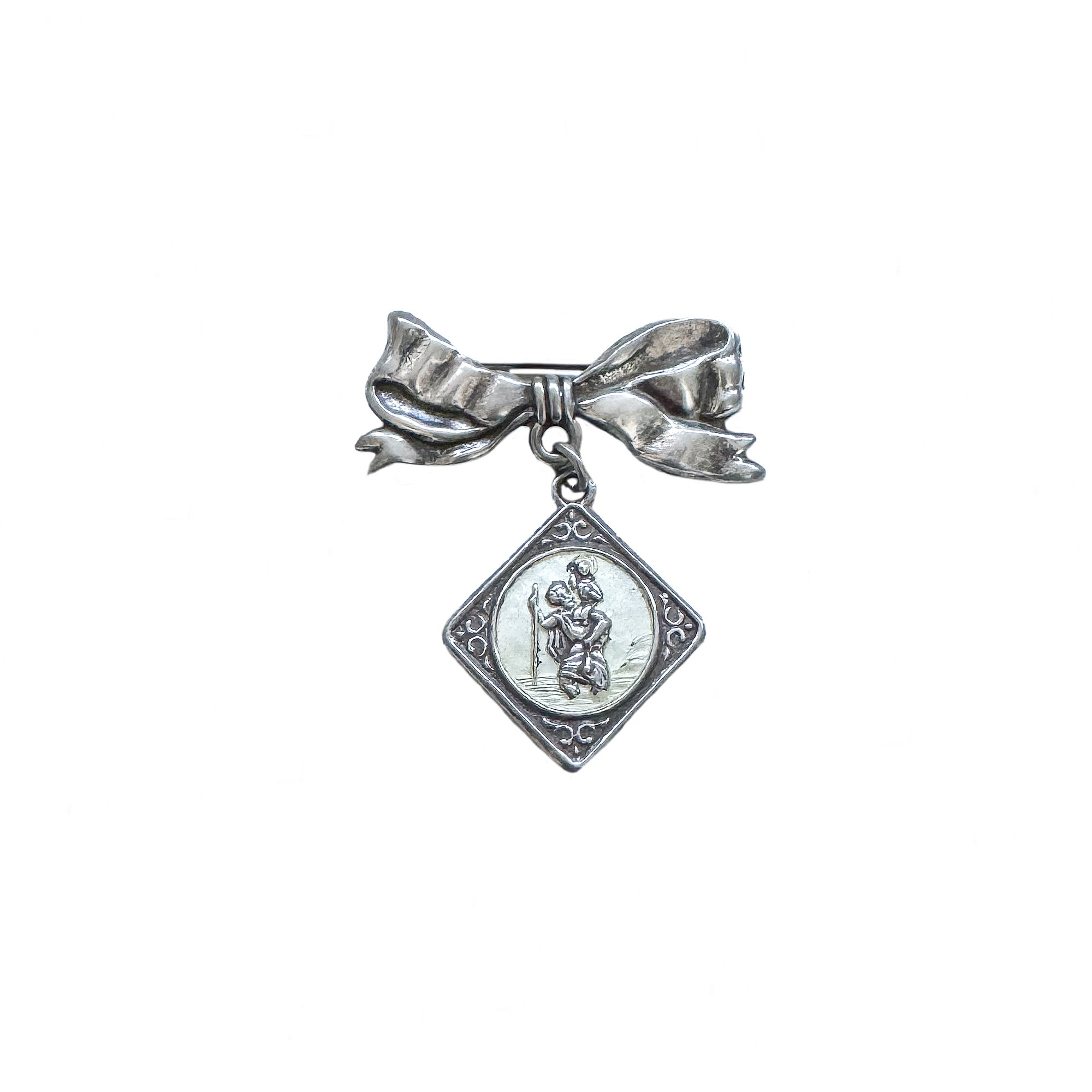 a silver bow brooch with dangling st Christopher pendant