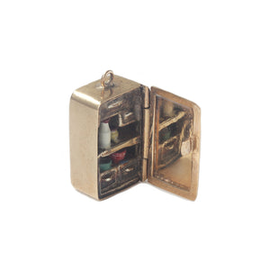 A yellow gold vintage miniature fridge charm which opens with enamel items inside